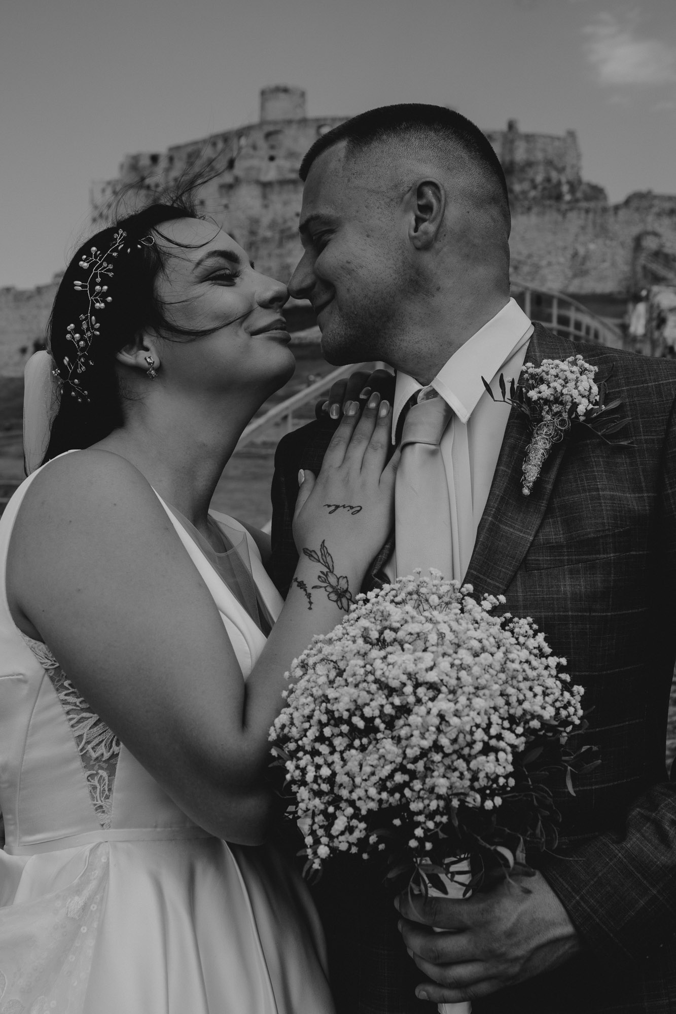 Svadobný pár Dominika a Marián sa objímajú pred impozantným výhľadom zo Spišského hradu, v pozadí vidieť okolité kopce.